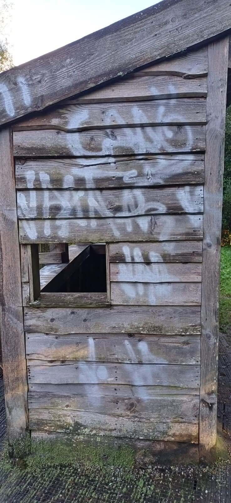 White spray paint across the timber side of the bird hide in Camelford