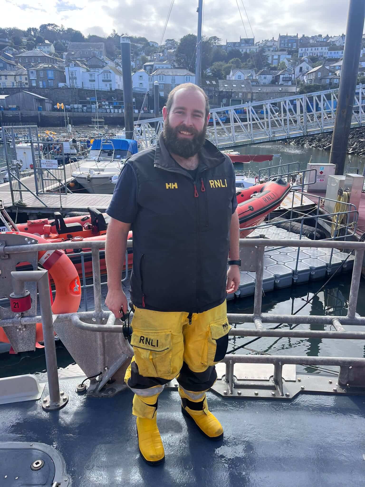 Penlee Lifeboat volunteer in RNLI kit standing on the deck of the lifeboat in the harbour