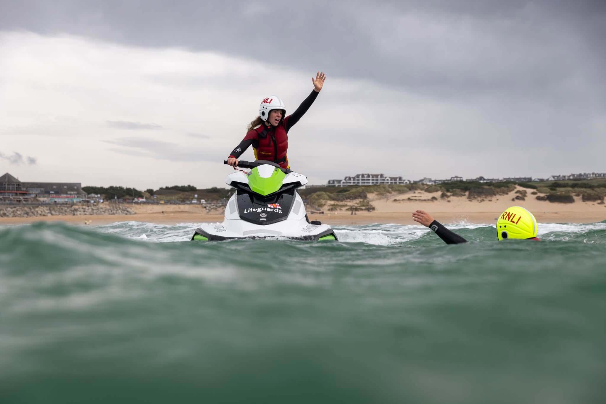 A lifeguard on a rescue watercraft signalling with a raised arm