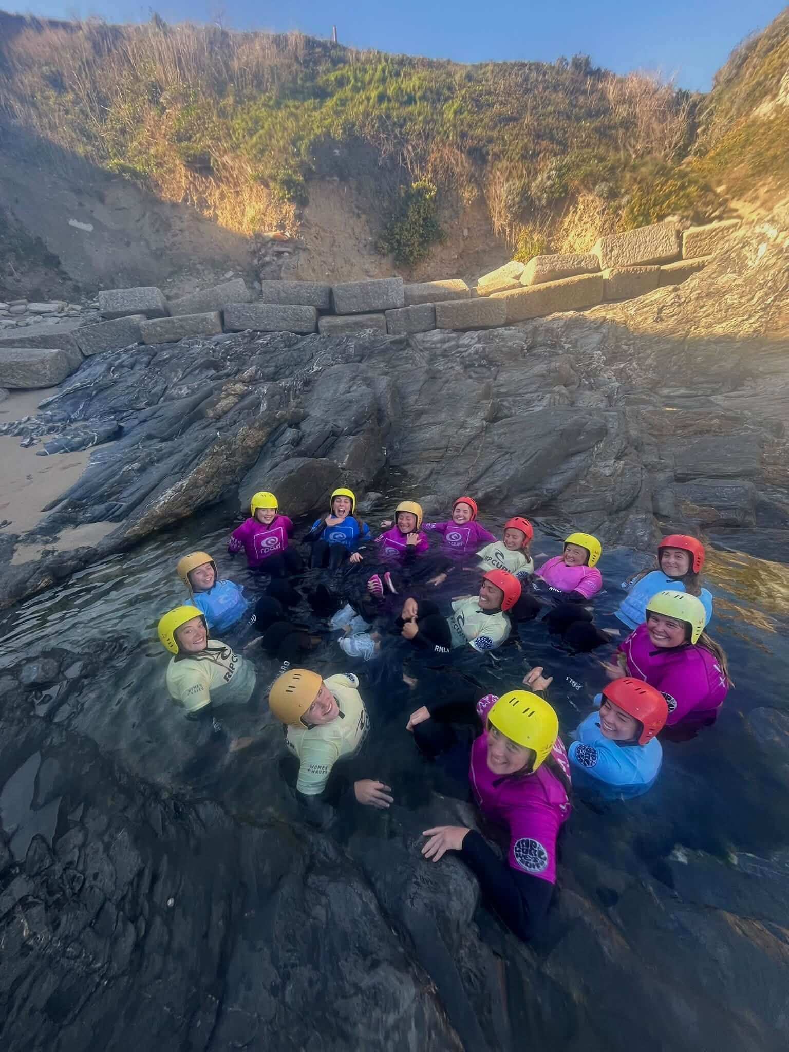 A group in helmets sitting in a rock pool