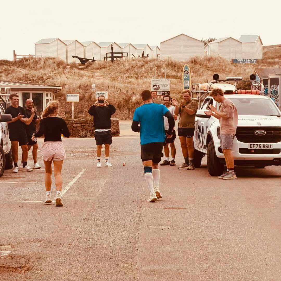 Supporters applauding beside an RNLI lifeguard truck as a runner comes in