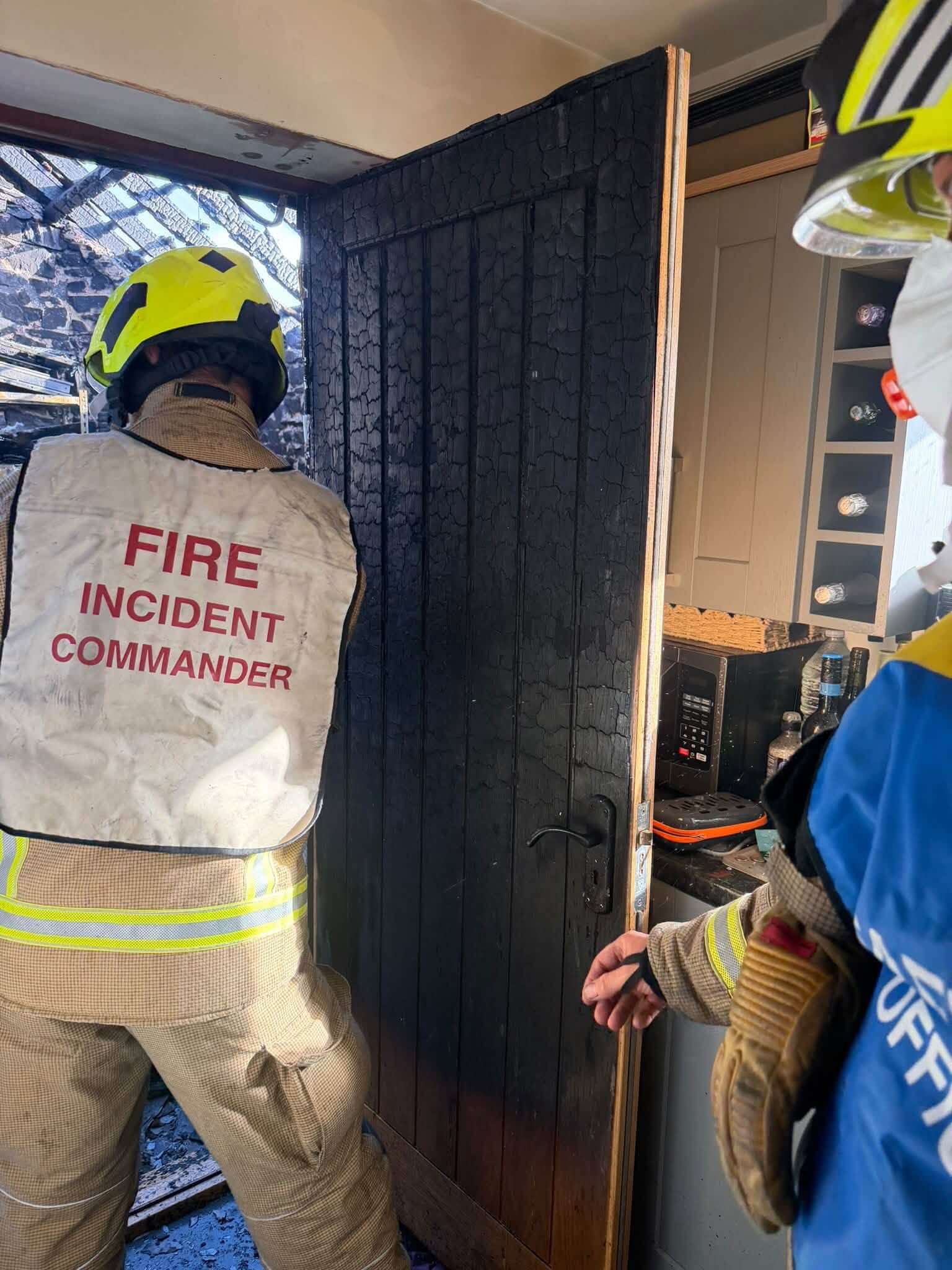 Charred side of the fire door with a fire incident commander looking into the damaged utility area