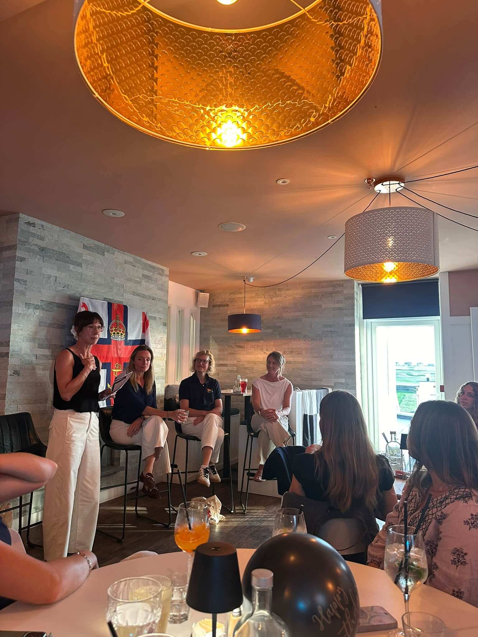 A speaker addressing a seated group at an evening talk