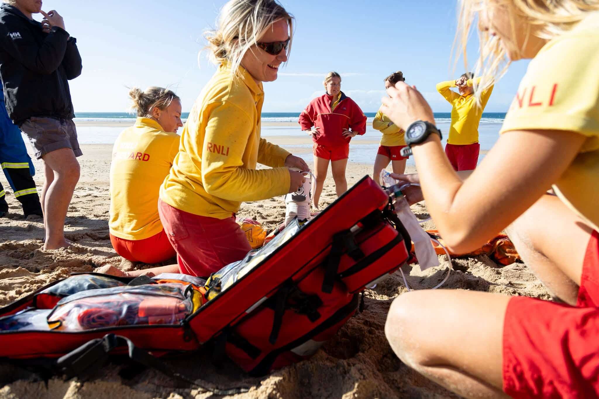 Lifeguards working with casualty care kit on the sand