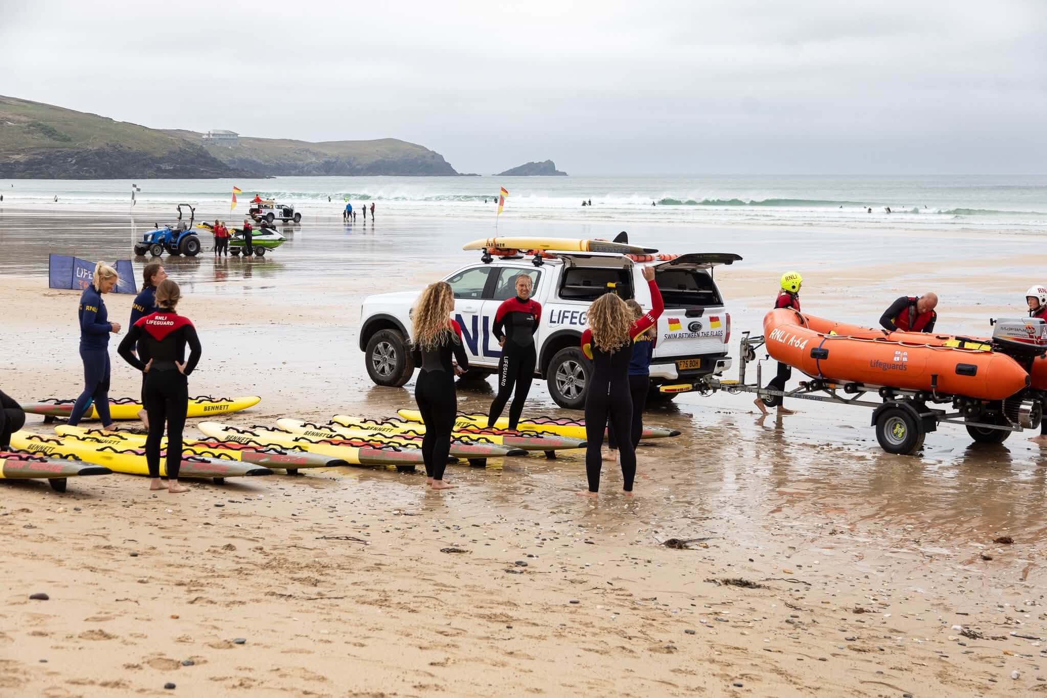 Lifeguards with rescue boards, a lifeguard truck and an inshore rescue boat on the beach