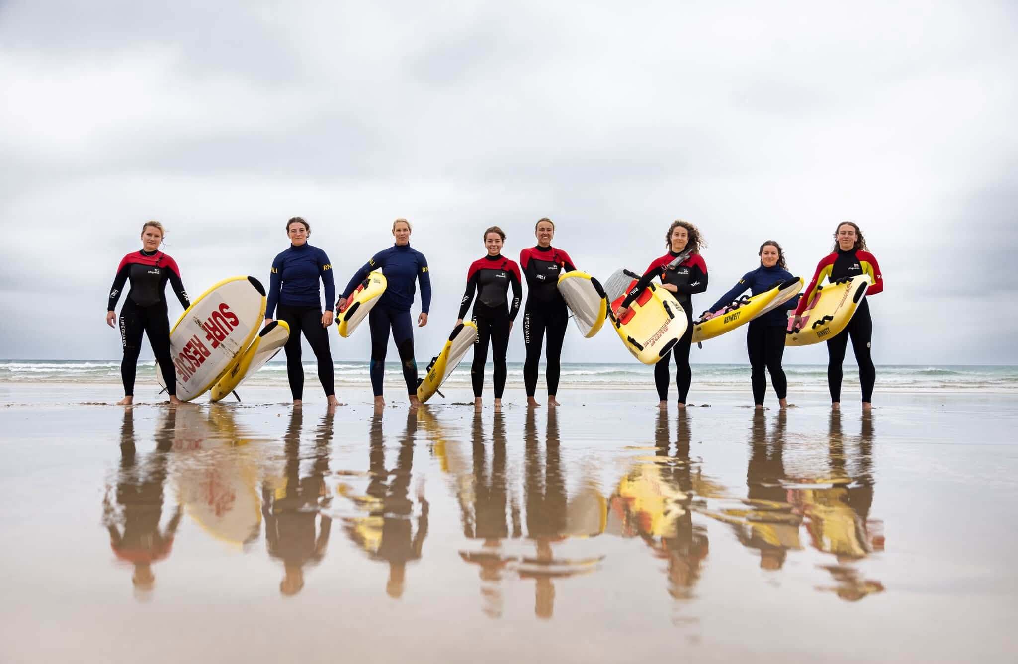 Women lifeguards holding rescue boards on a beach in Newquay