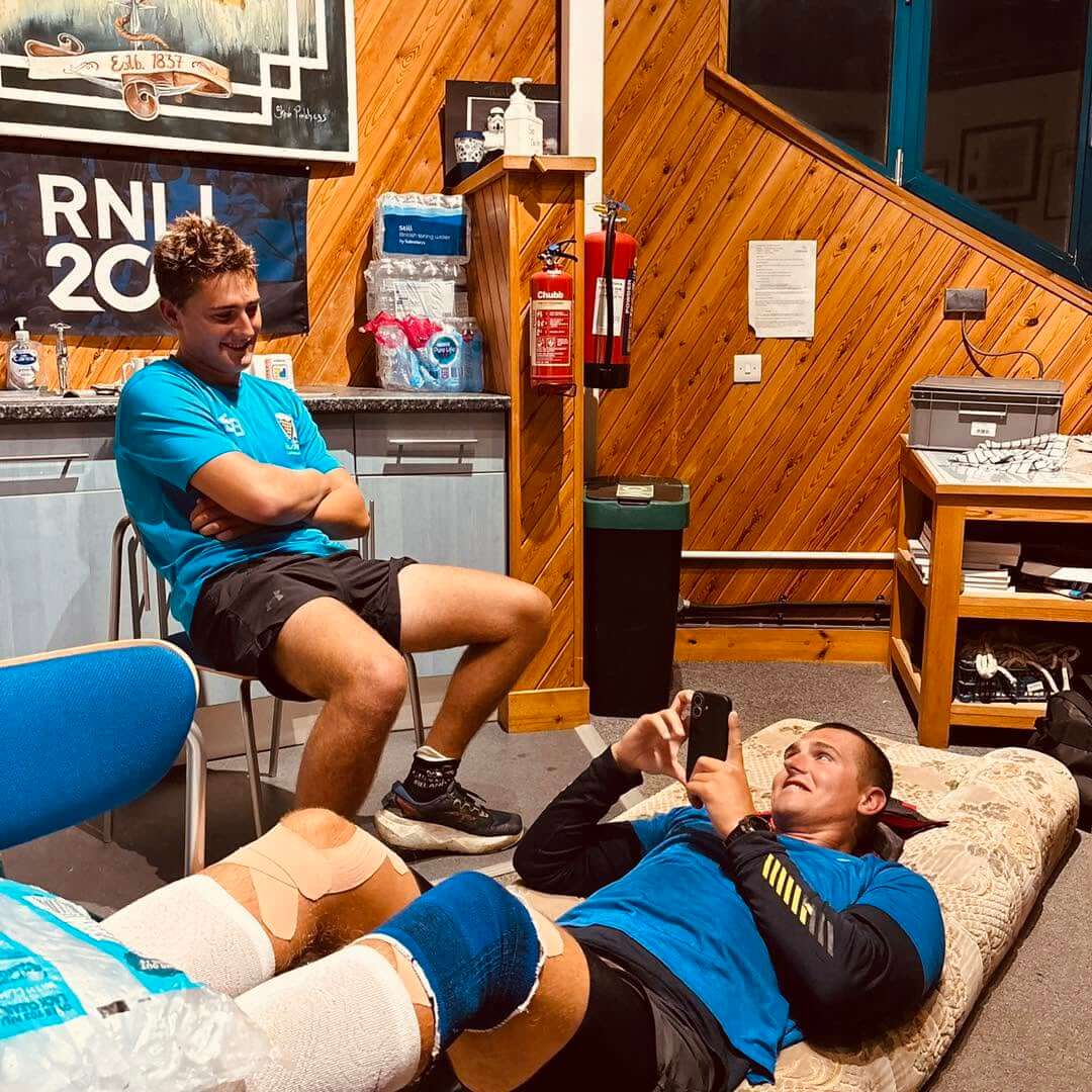 Runner with strapped knees resting on a mattress inside the lifeboat station