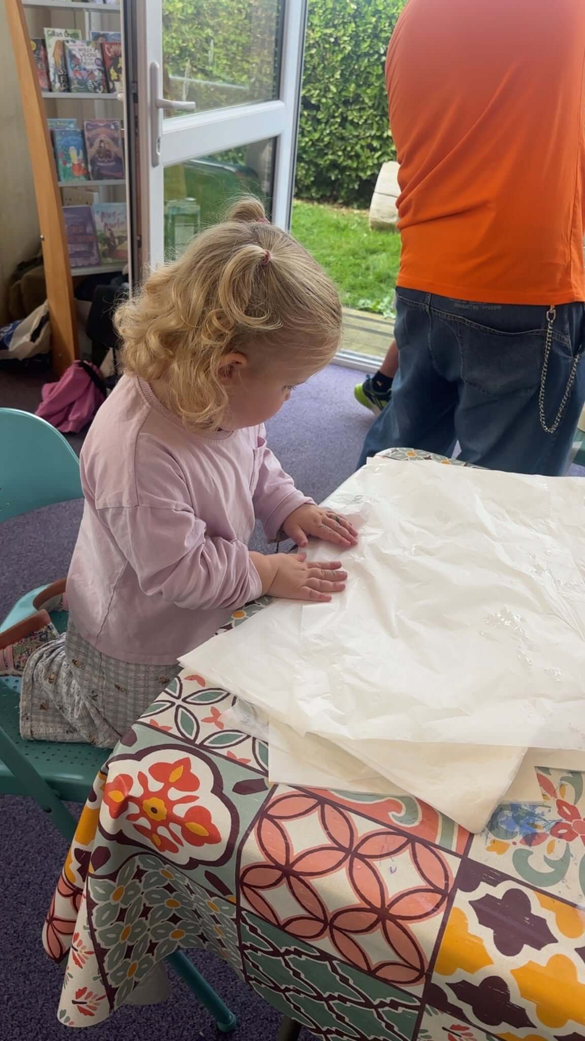 A young child smoothing tissue paper on a table at Newquay Library