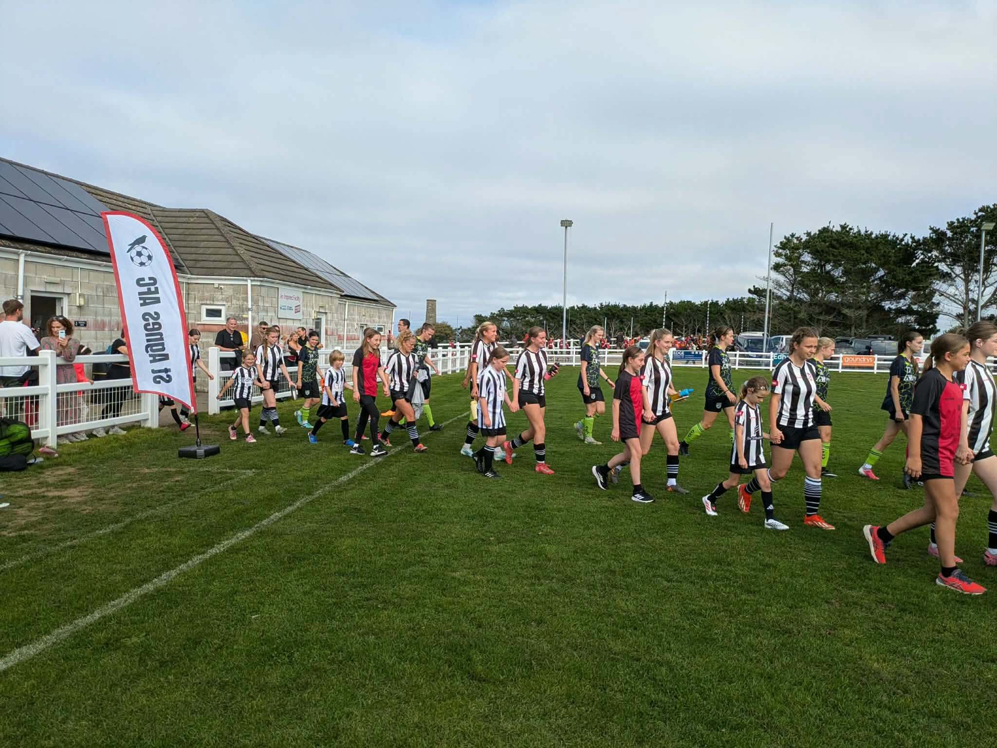 Players and young mascots walking out onto the pitch at St Agnes AFC