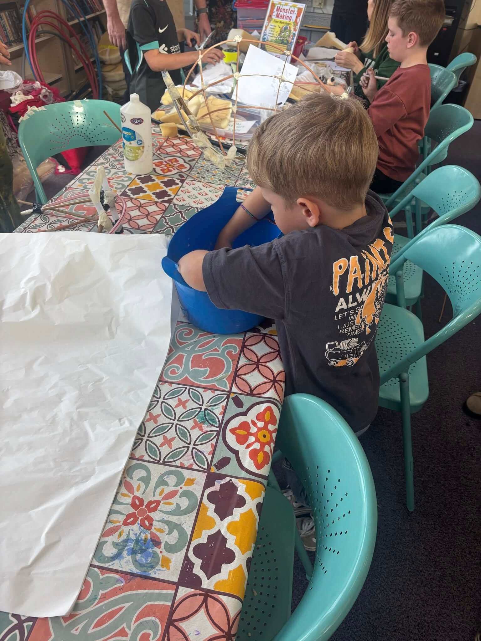 A child mixing paste in a blue tub at the Monster Making Workshop at Newquay Library