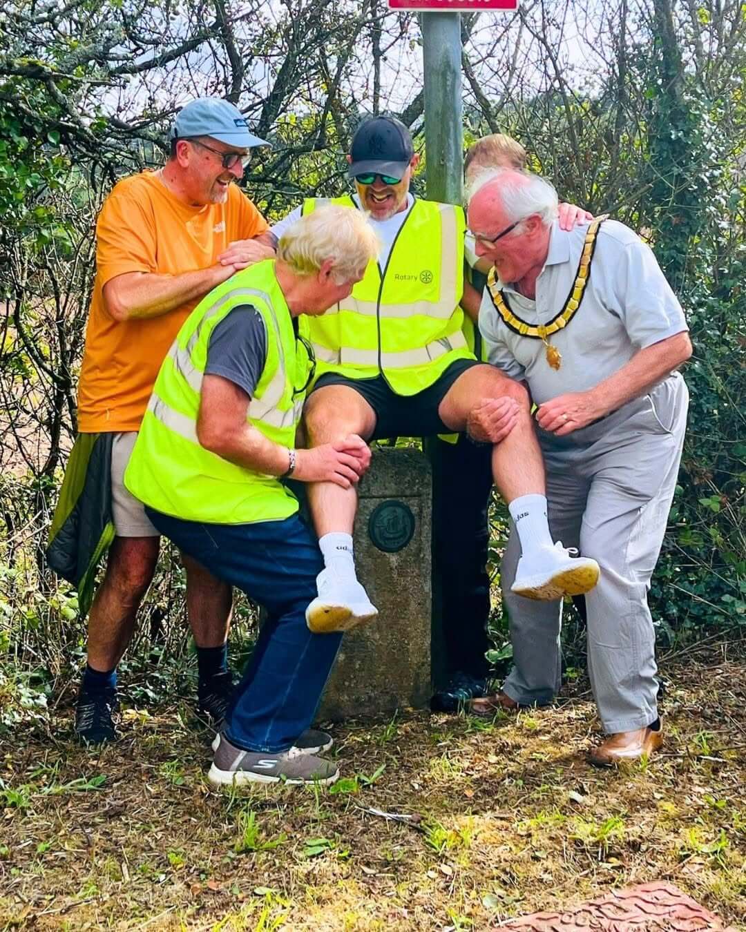 A walker in a hi-vis vest being bounced on a boundary stone