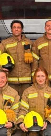 Firefighters in kit holding yellow helmets at Fowey Community Fire Station