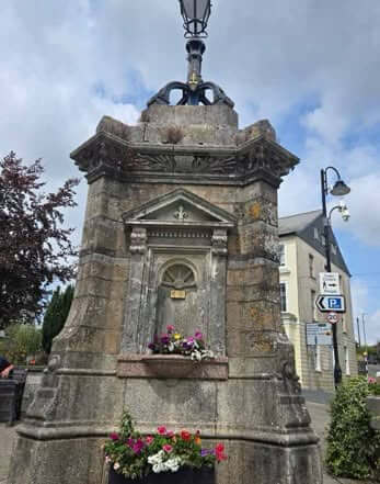 The Fountain on Barras Street in Liskeard, a stone drinking fountain with flower planters