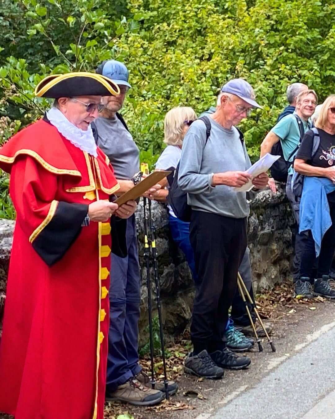 Town Crier in red robes and tricorn hat reading the cry to walkers