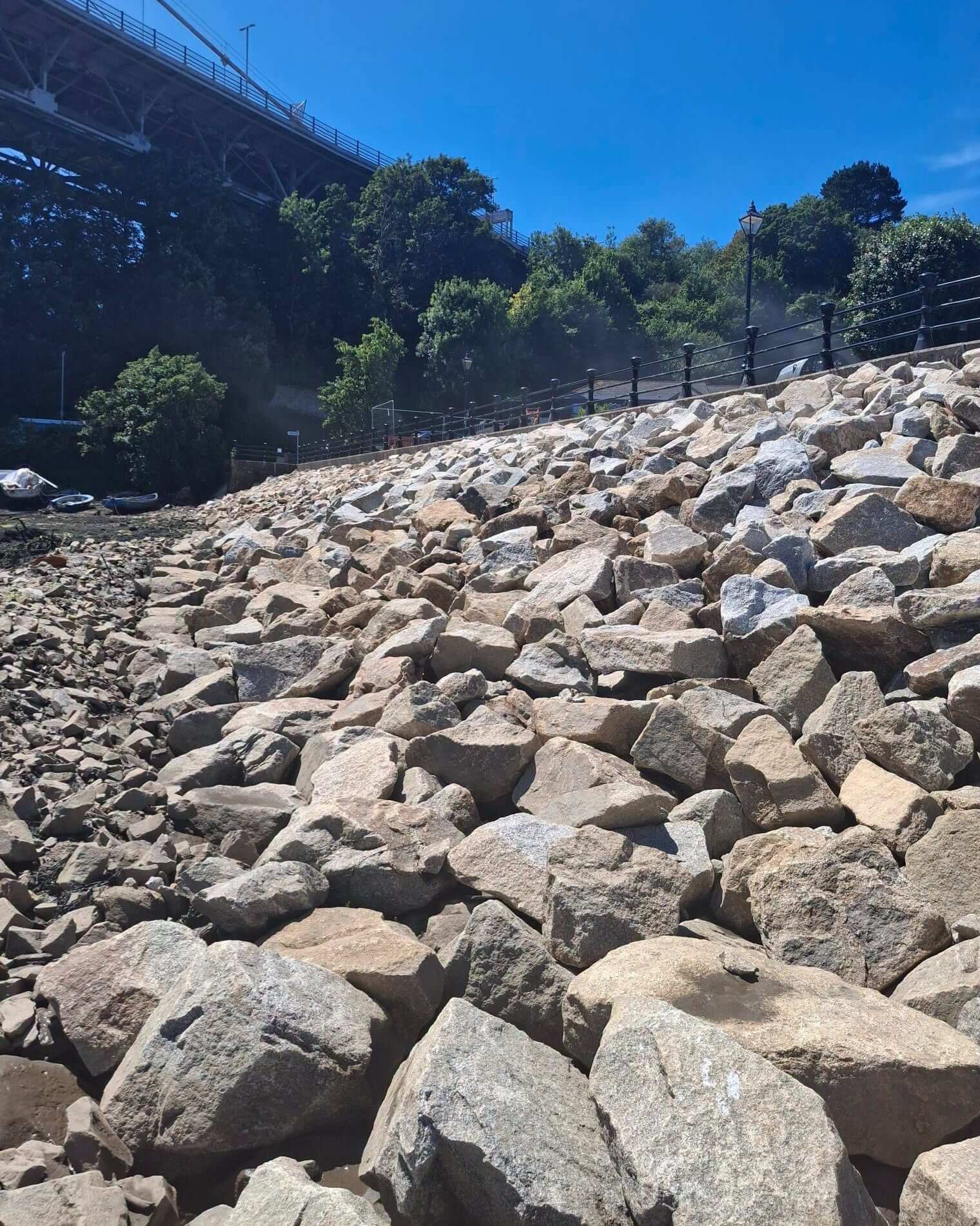 Rock armour along the seawall at Jubilee Green under a blue sky