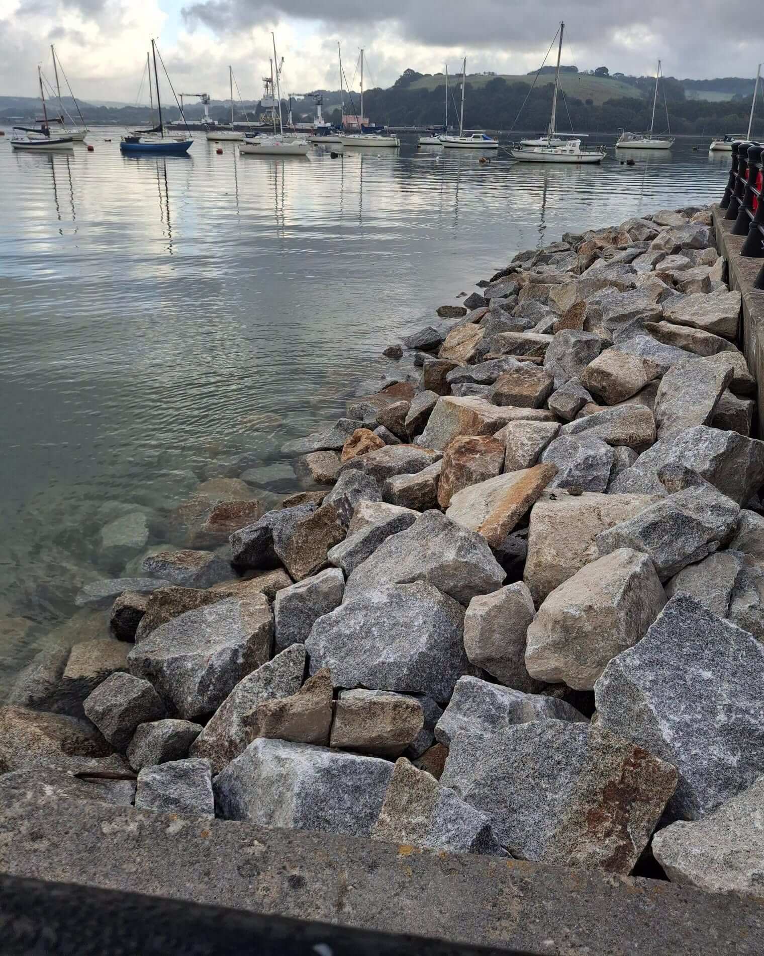 Rock armour at the water's edge at Jubilee Green with moored yachts