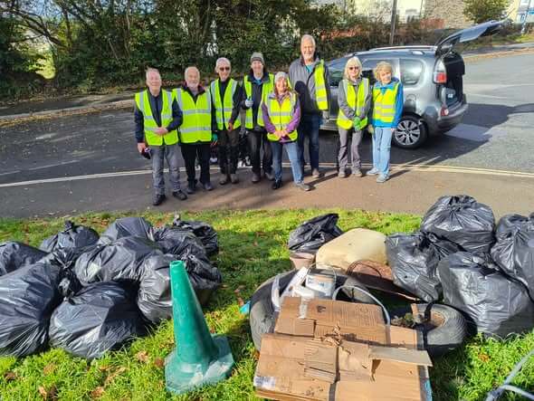 Bodmin Tidy it Team volunteers in hi-vis vests standing behind bags of collected rubbish
