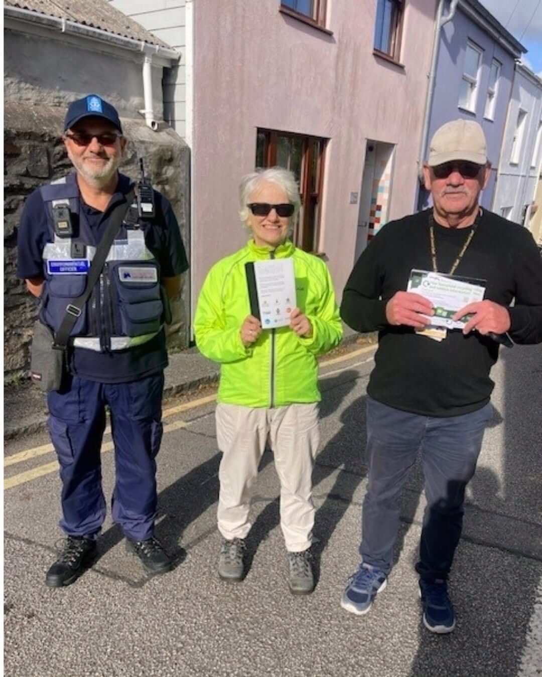 An environmental officer and two volunteers holding leaflets on a Falmouth street