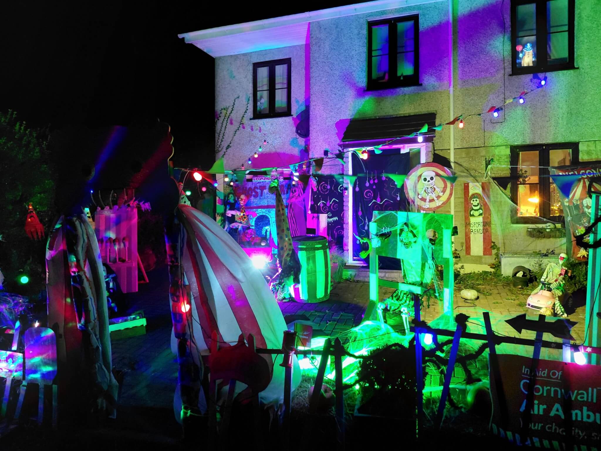 Halloween circus display lit in neon colours outside a house in St Day