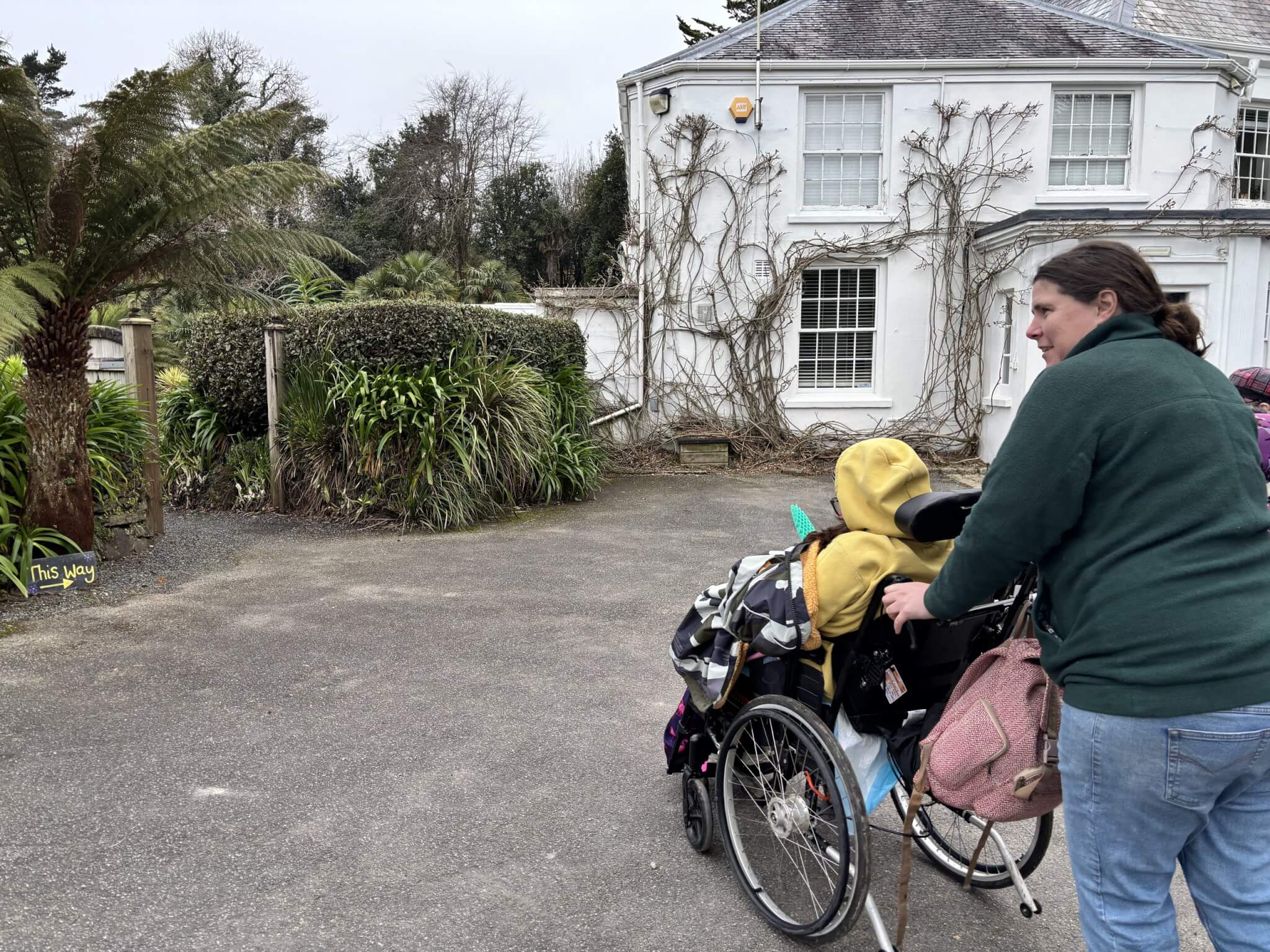 Two people, one using a wheelchair, in front of a white house