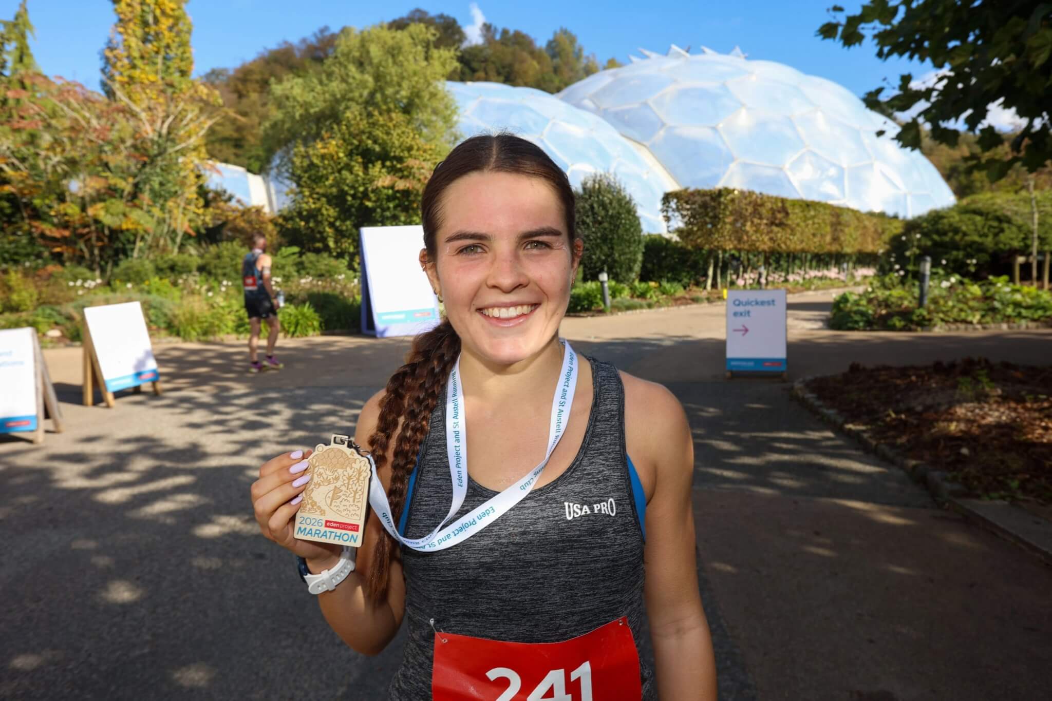 Annie Wisely with her medal in front of the Eden Project Biomes