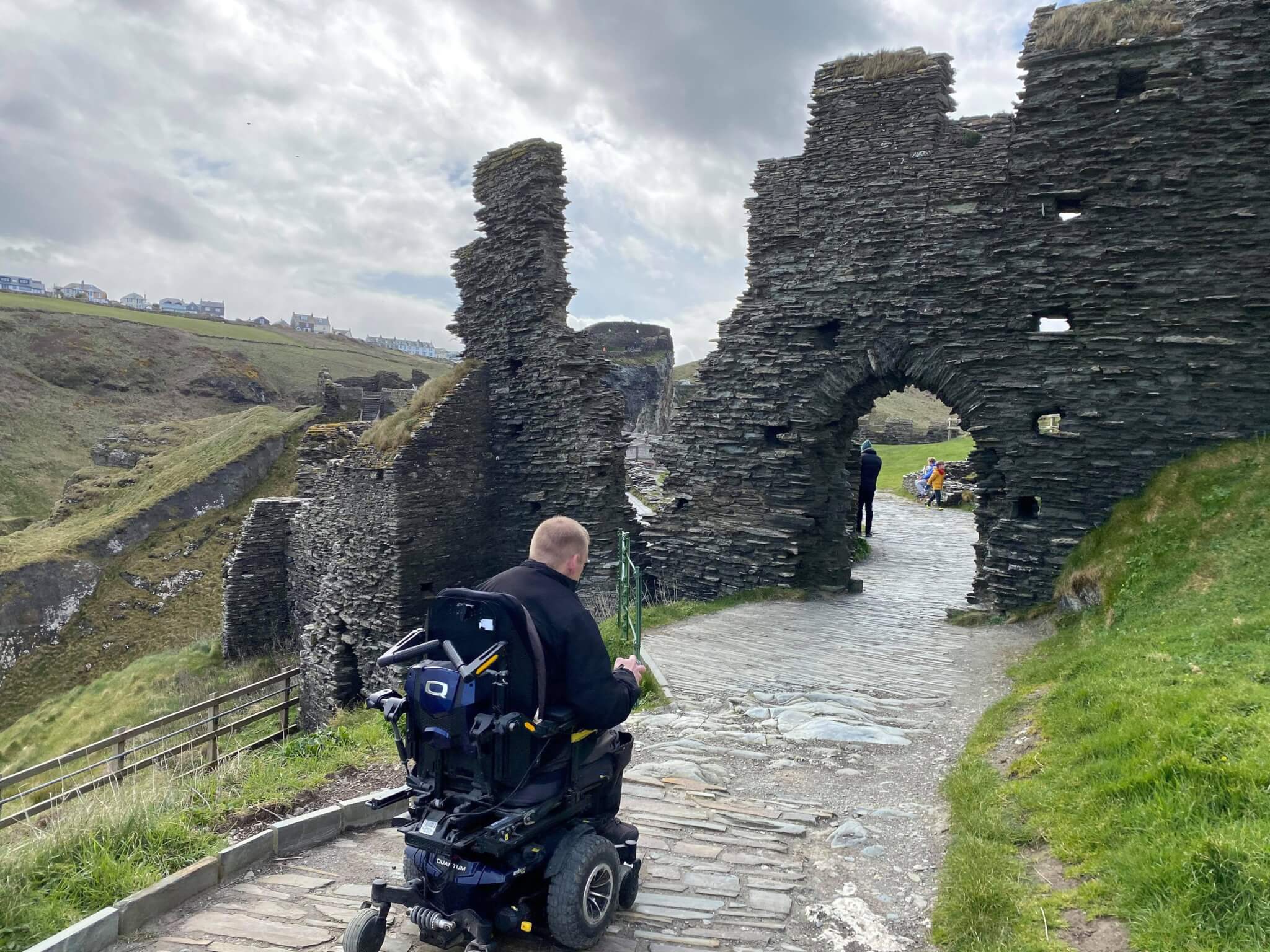 A powerchair user on the stone path at Tintagel Castle