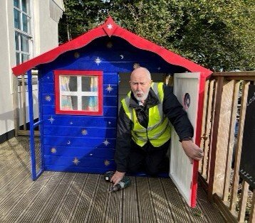 Looe Shedders volunteer fitting a painted playhouse