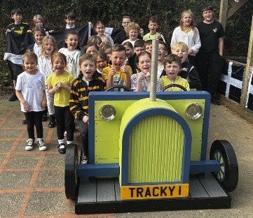 Schoolchildren with a wooden play tractor built by Looe Shedders