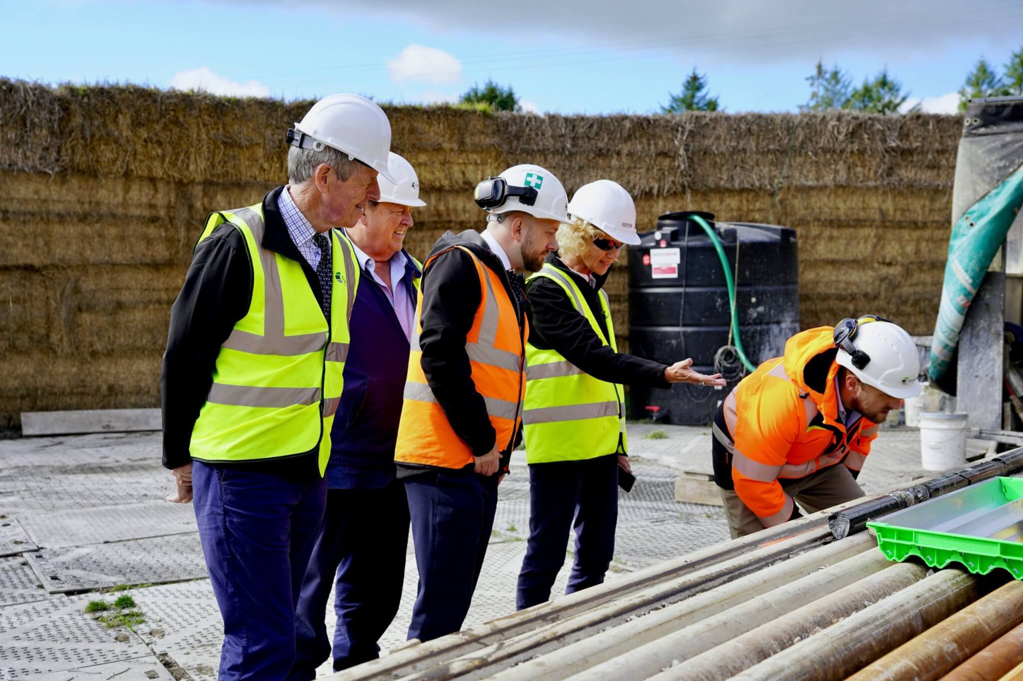 Visitors in hard hats inspecting drill rods at the Redmoor drill site