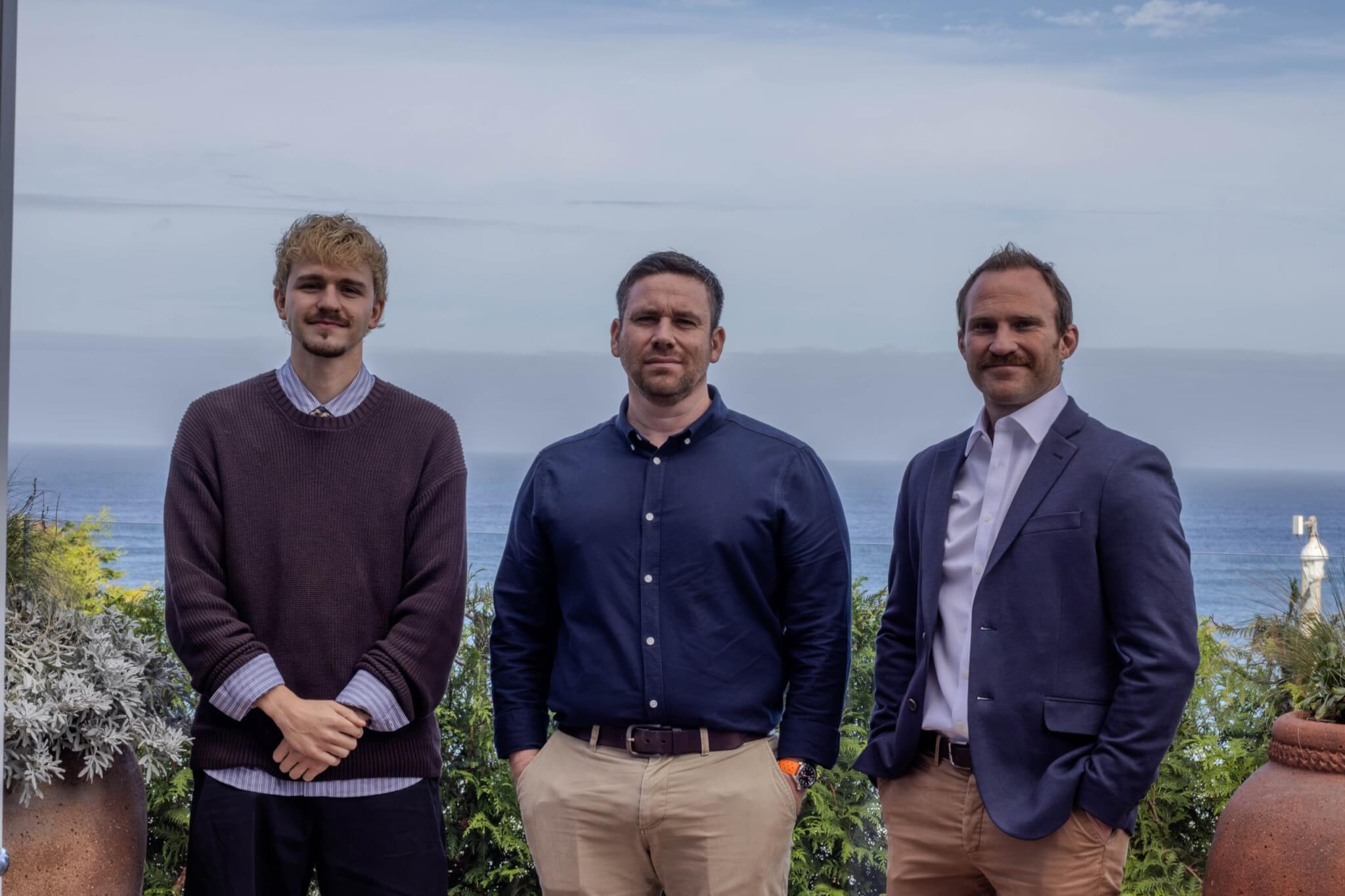 Three men standing on a terrace overlooking the sea in Cornwall