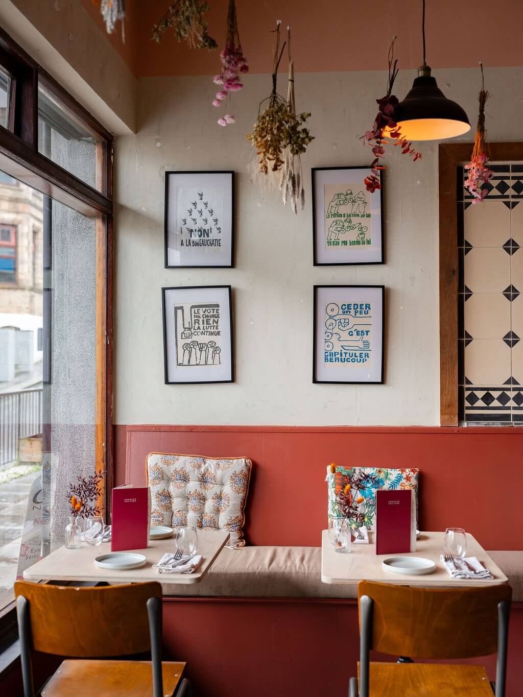 Restaurant tables beneath hanging dried flowers and framed prints
