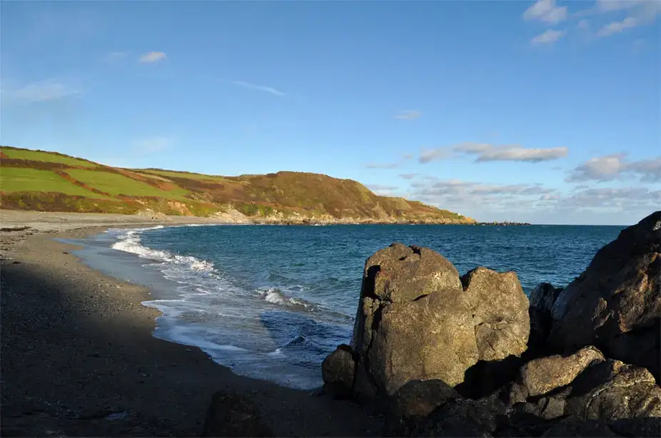 A shingle beach and low headland in evening light near Coverack