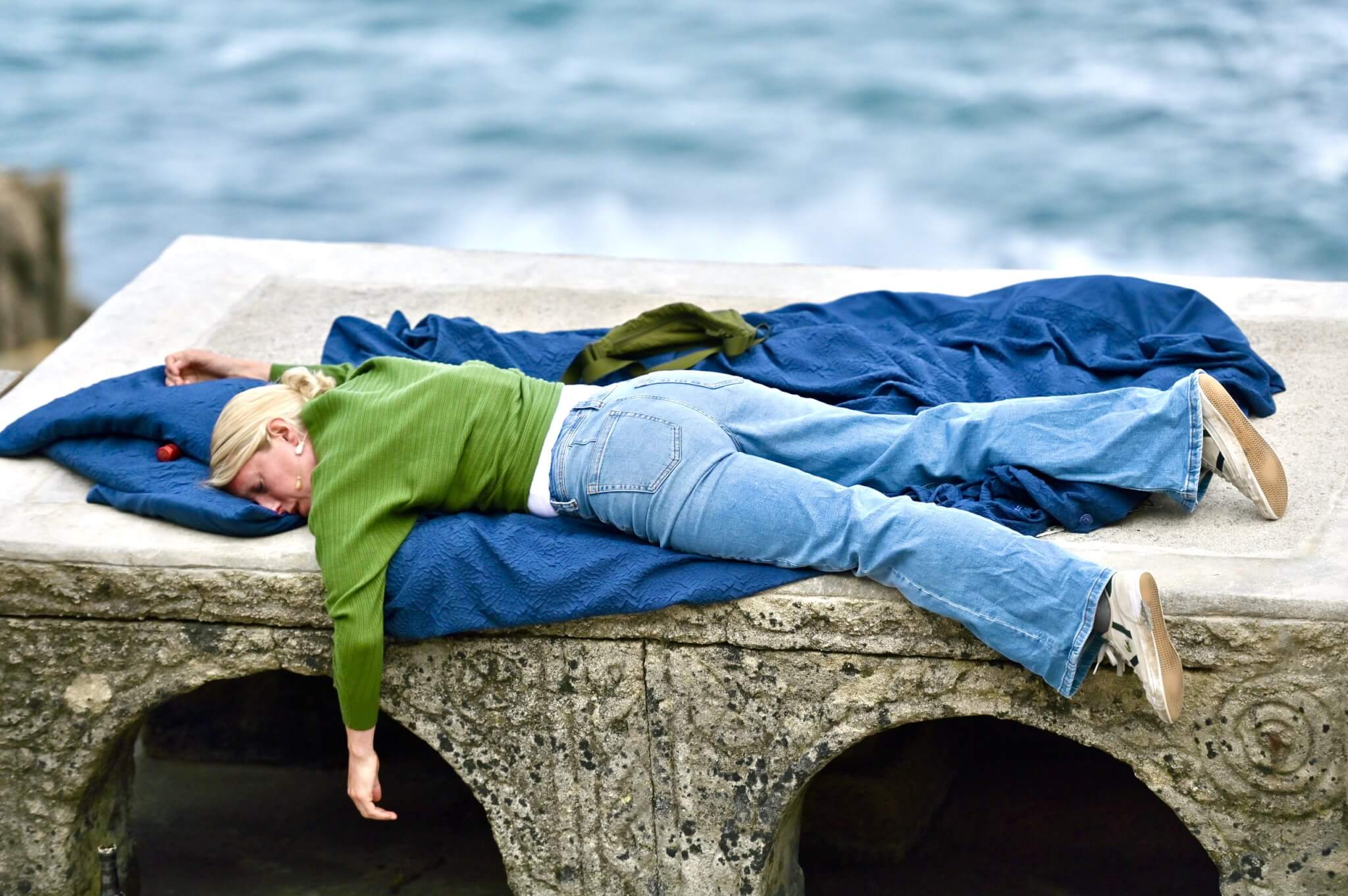 Actor lying on a stone wall above the sea in The Girl on the Train at the Minack