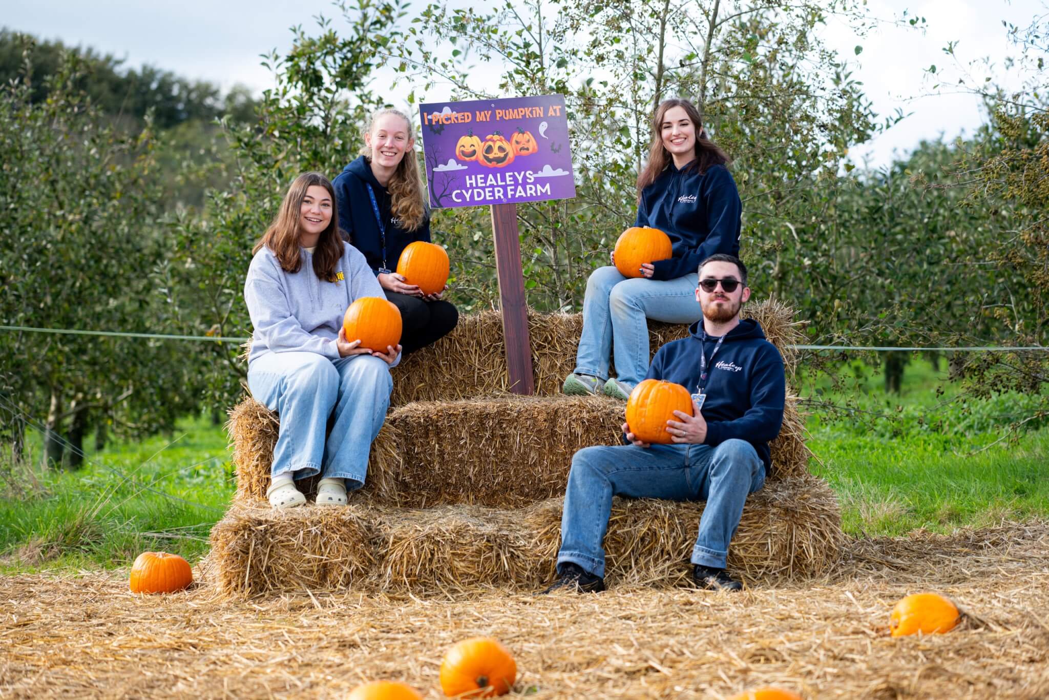 Healey's team on hay bales by a pumpkin patch sign
