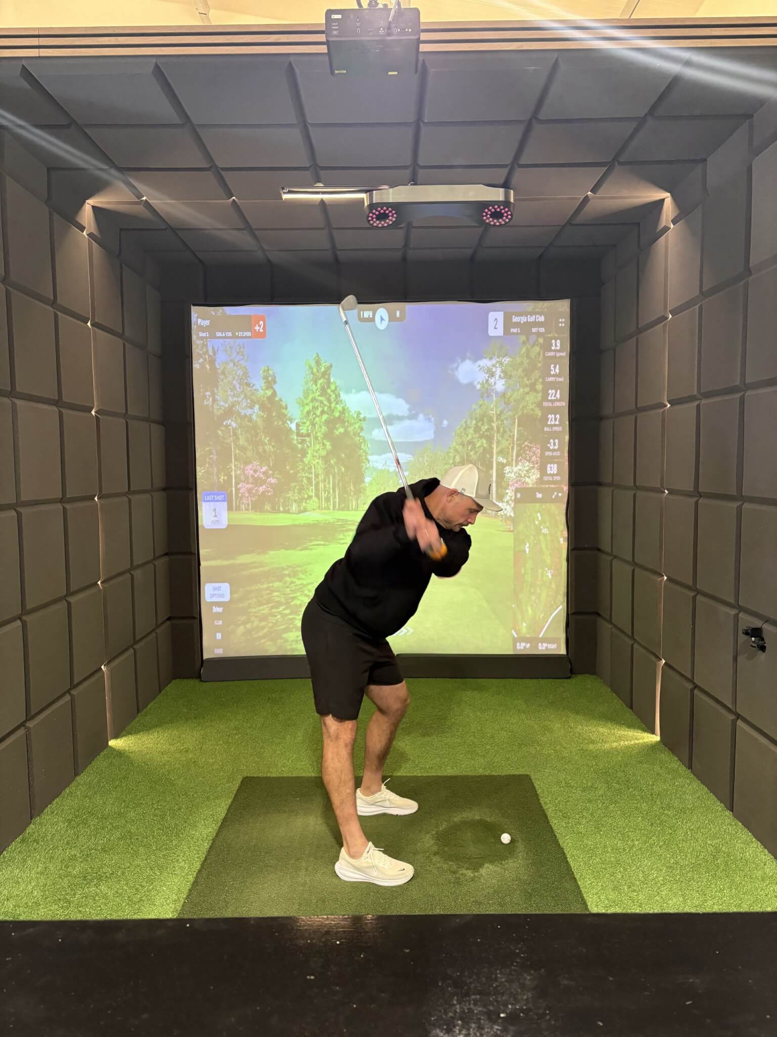 Dan O'Shaughnessy mid-swing in a golf simulator bay at OSH Golf
