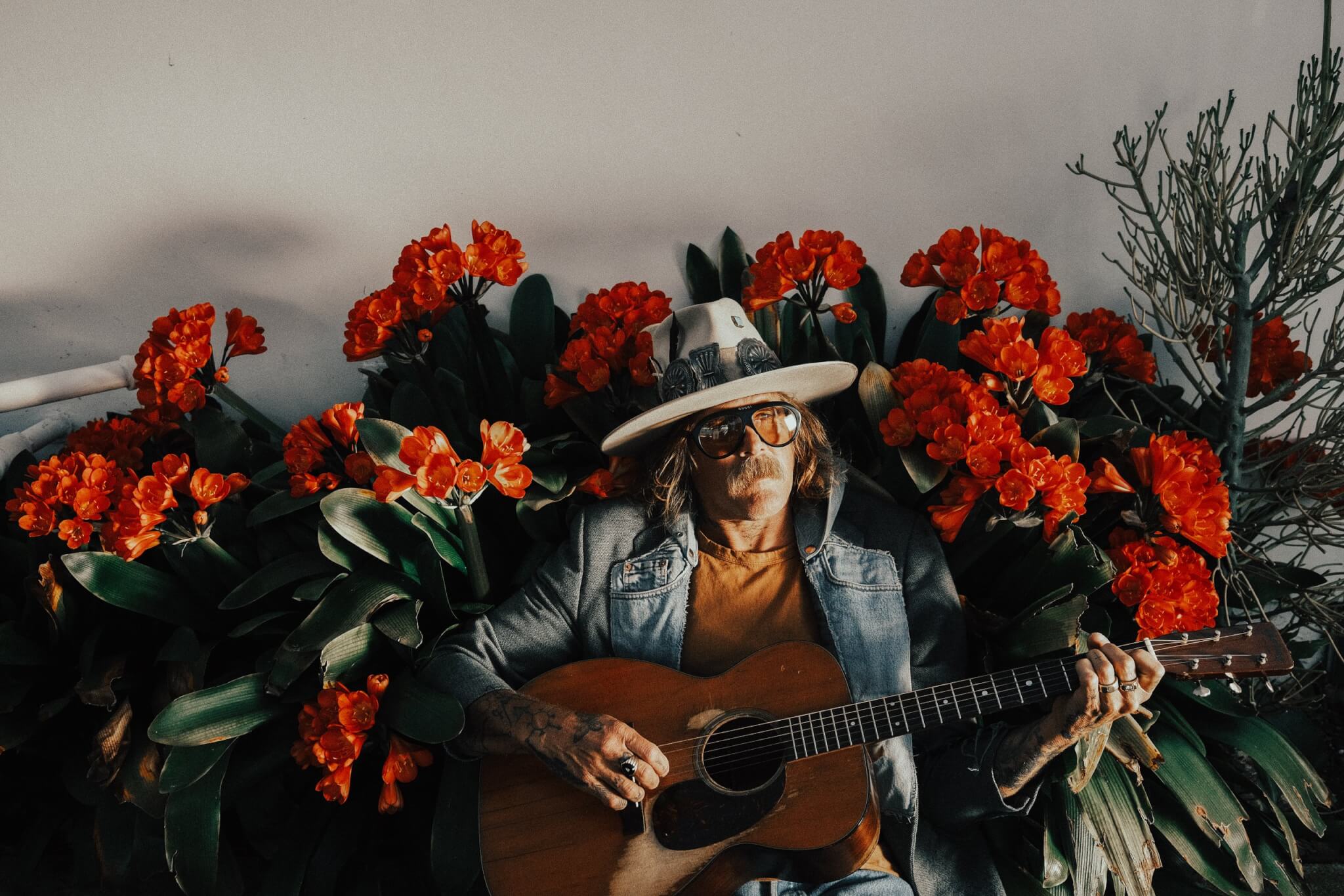 Donavon Frankenreiter playing guitar among red flowers