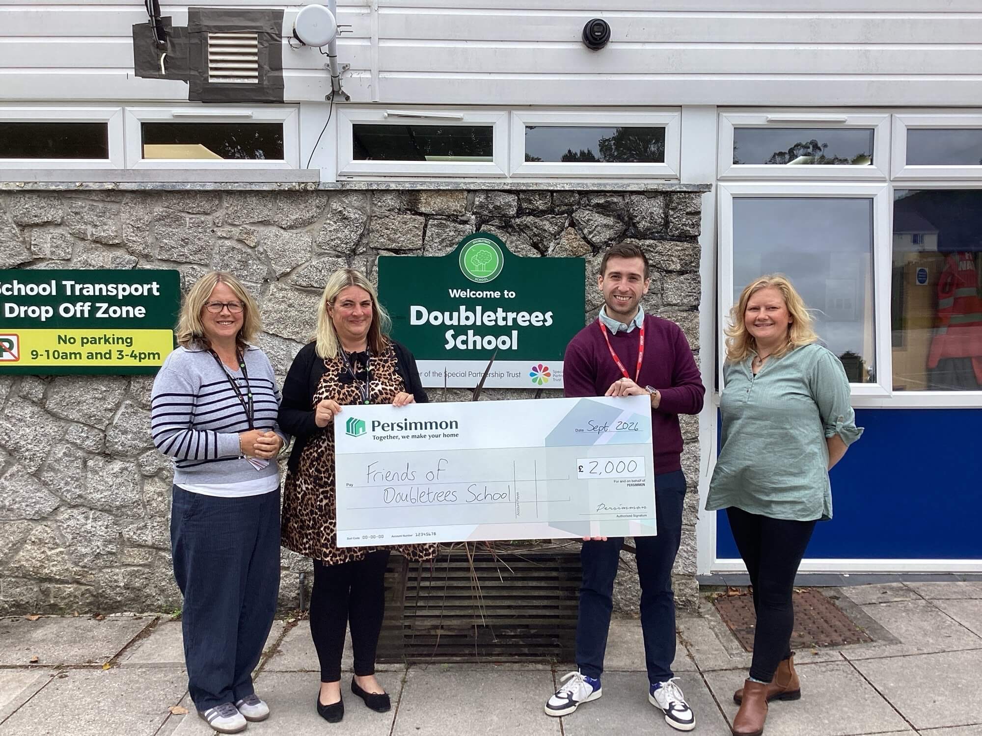 Staff from Doubletrees School and Persimmon Homes with a £2,000 cheque outside the school in St Blazey