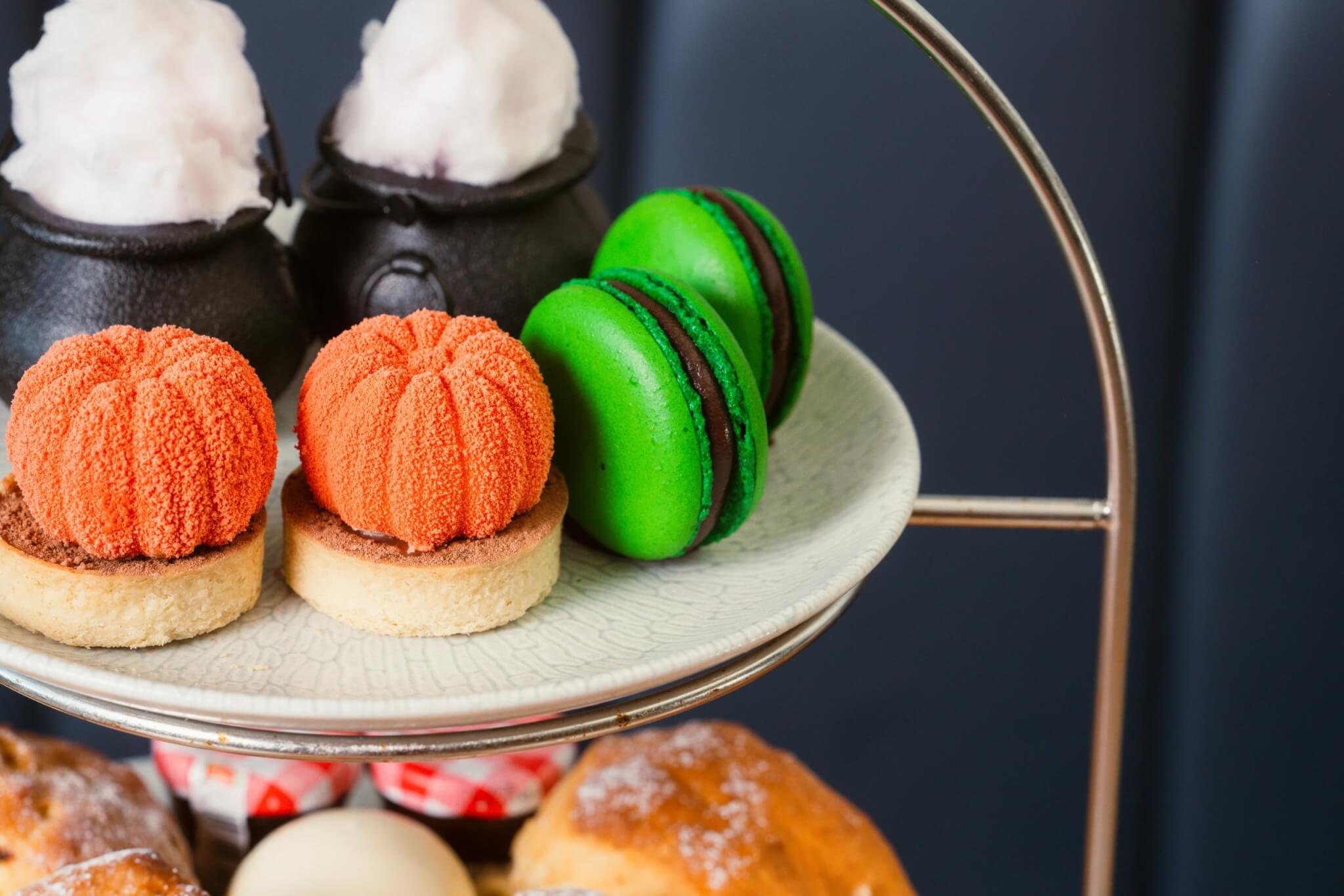 Pumpkin cheesecakes, cauldrons and green macarons close up