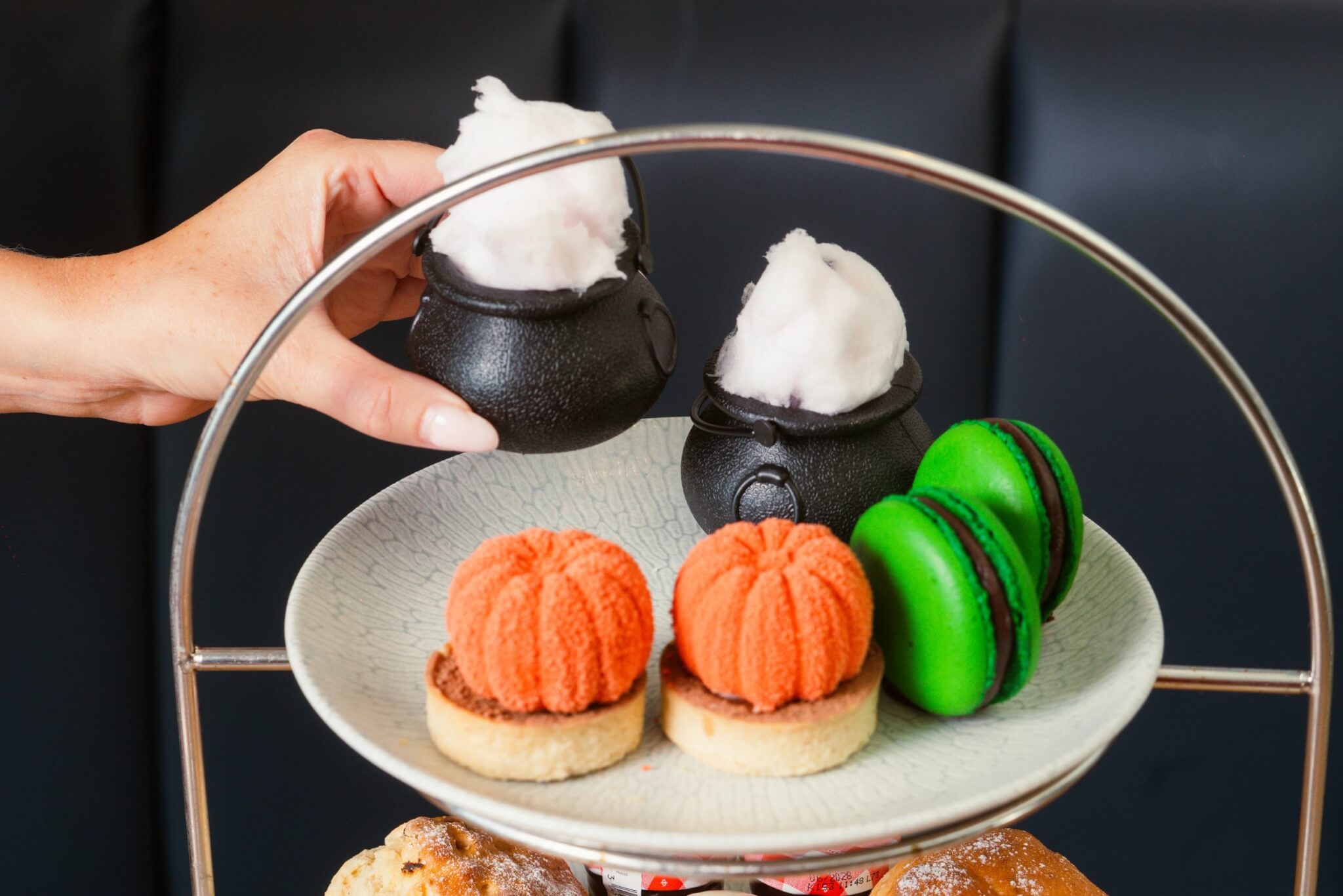 Hand lifting a lime jelly cauldron from the afternoon tea stand
