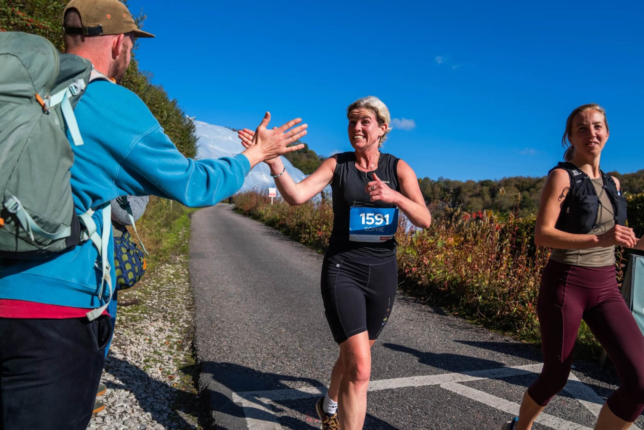 Runners high-fiving a supporter on the Eden Project Marathon route