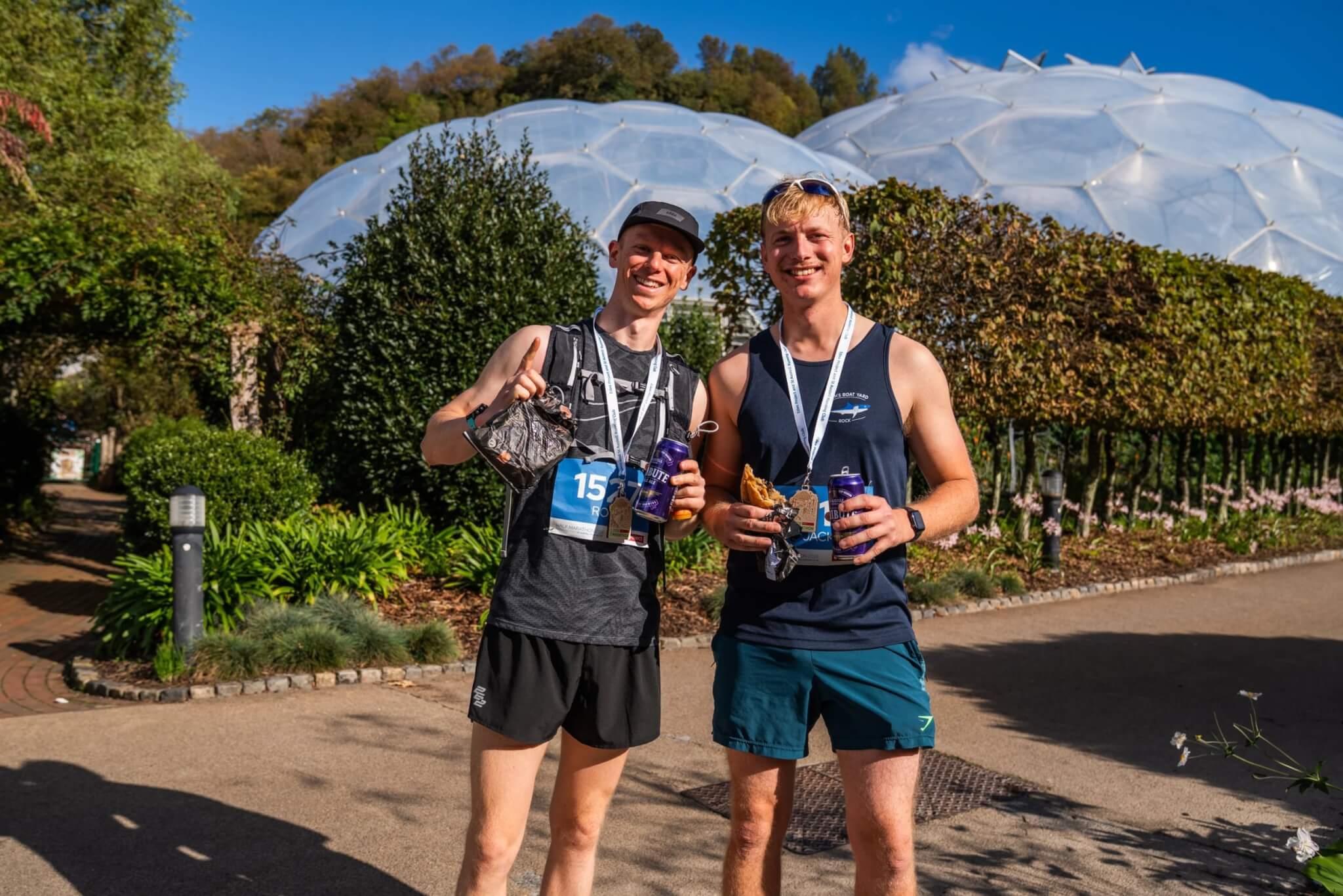 Two runners with medals and drinks in front of the Biomes