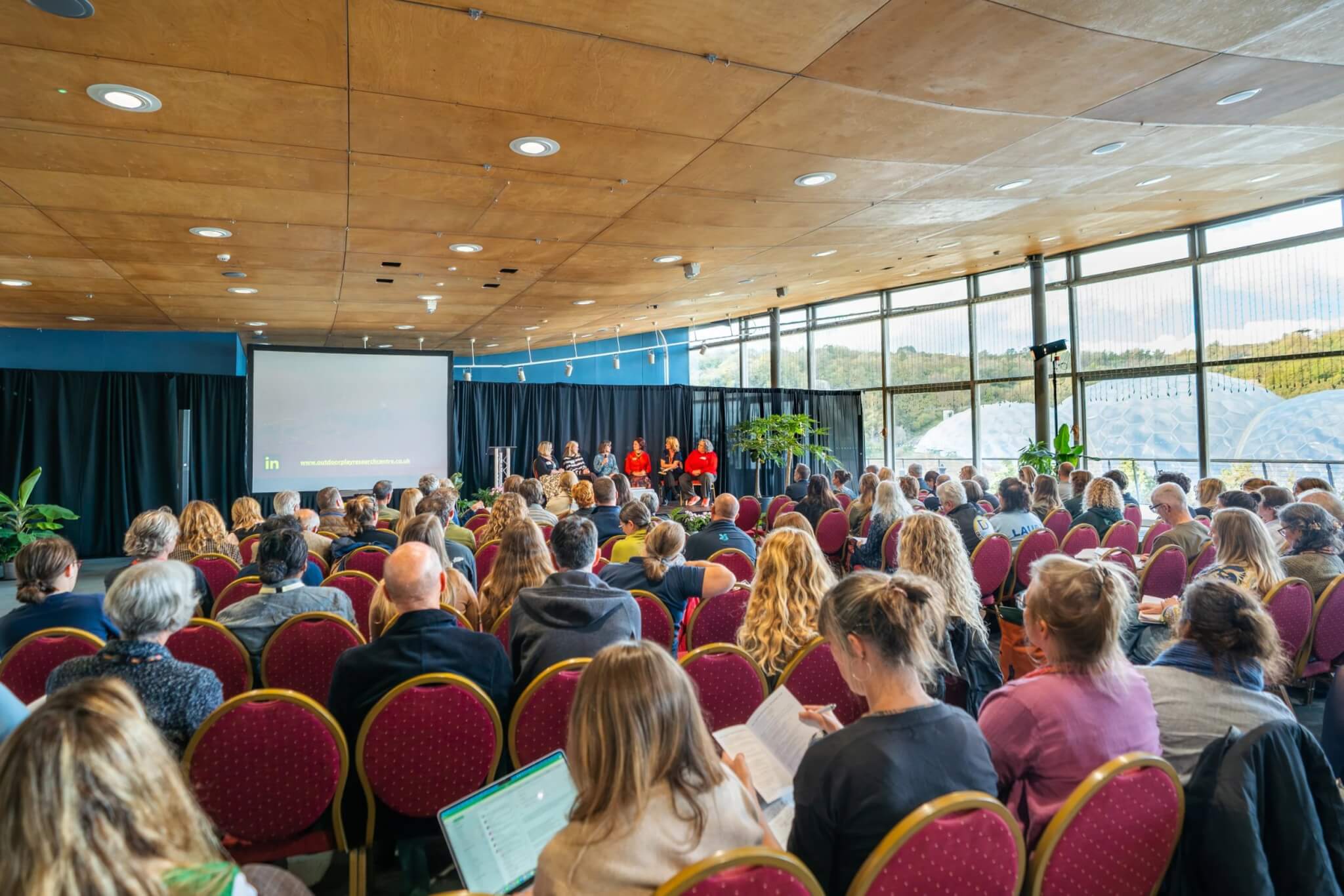 Audience at the Nature Connected Lives conference at the Eden Project, with the Biomes visible through the windows