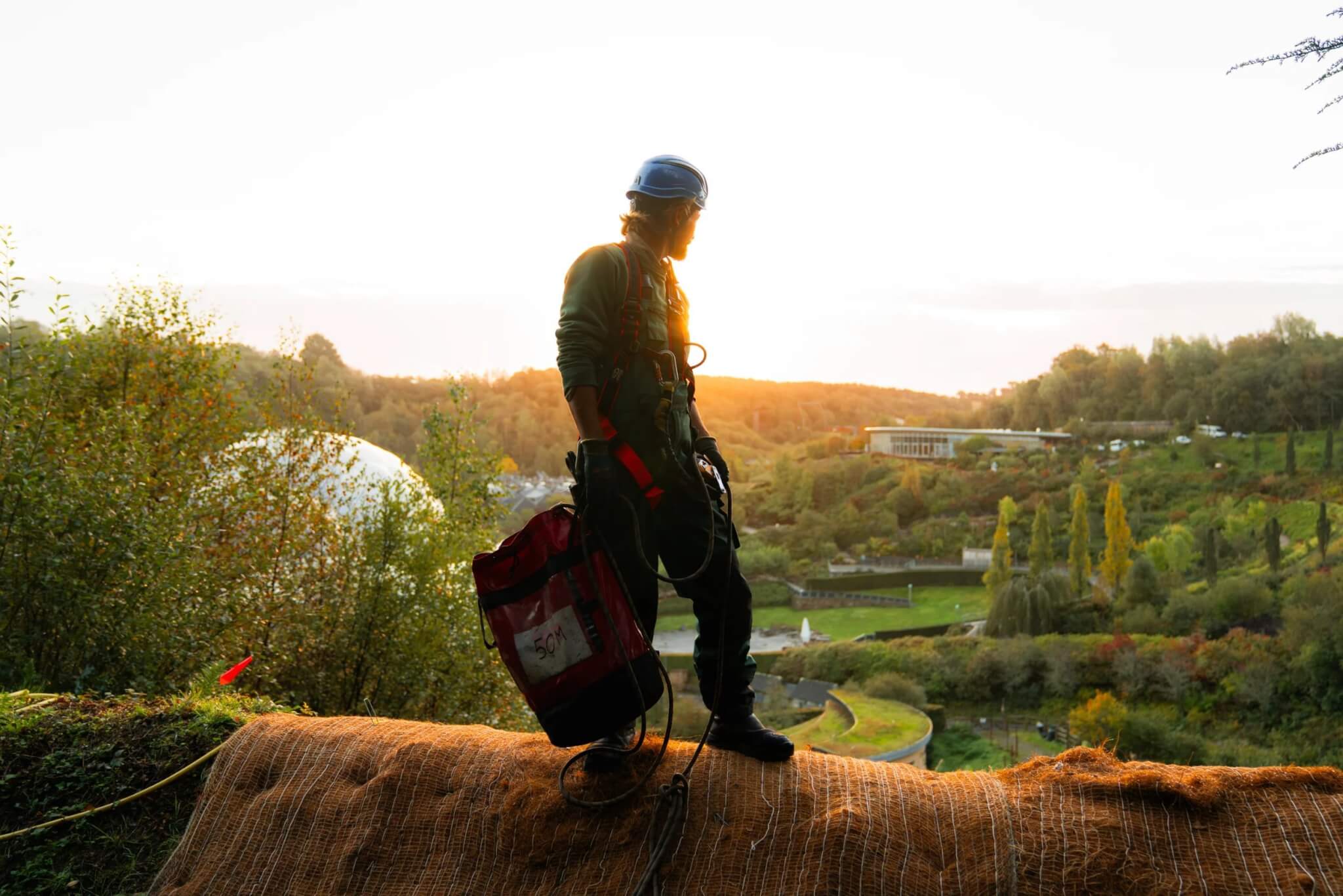 Eden Project gardener on ropes silhouetted at sunrise