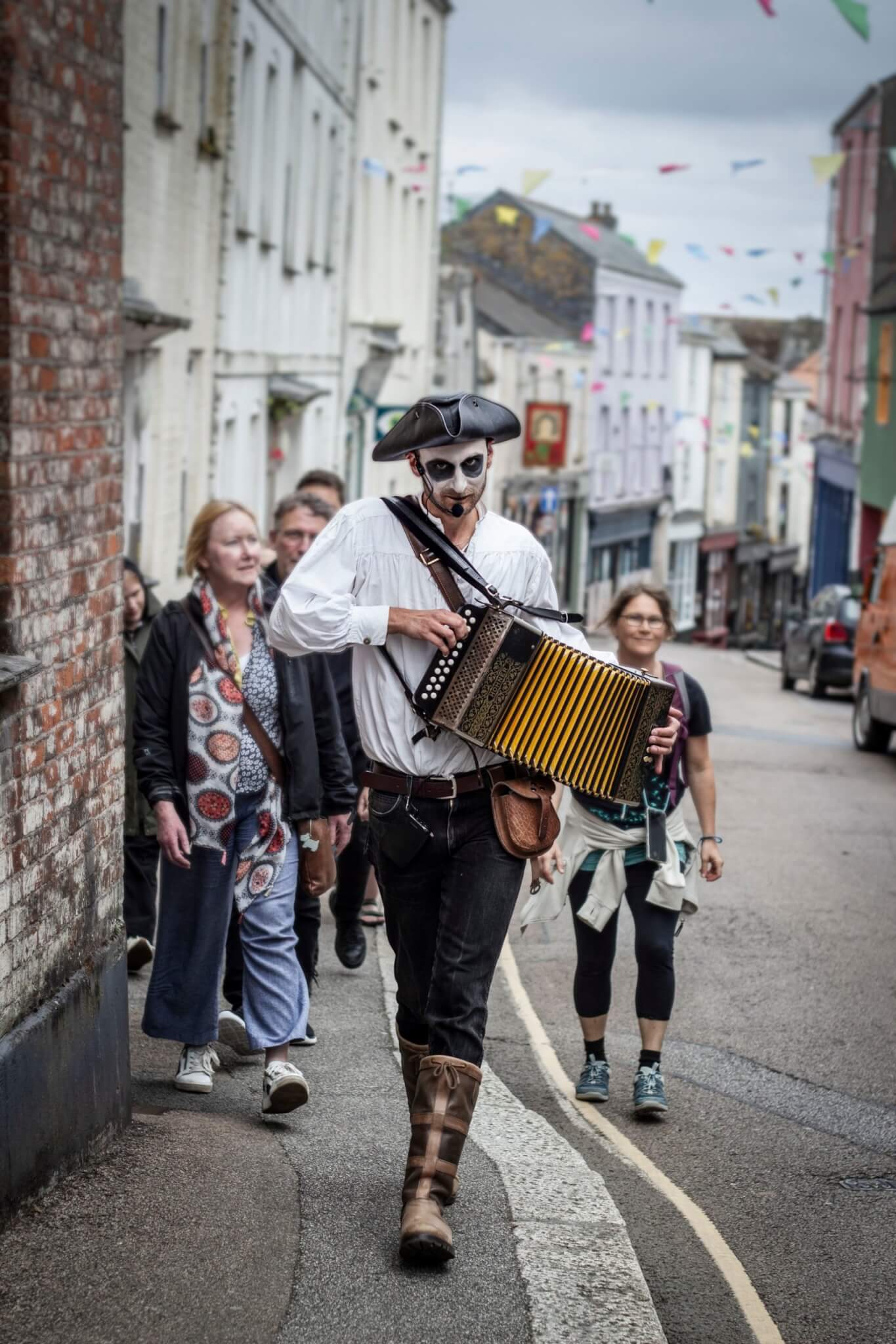 Falmouth Uncovered Ghost Tour guide playing an accordion leading a group through Falmouth