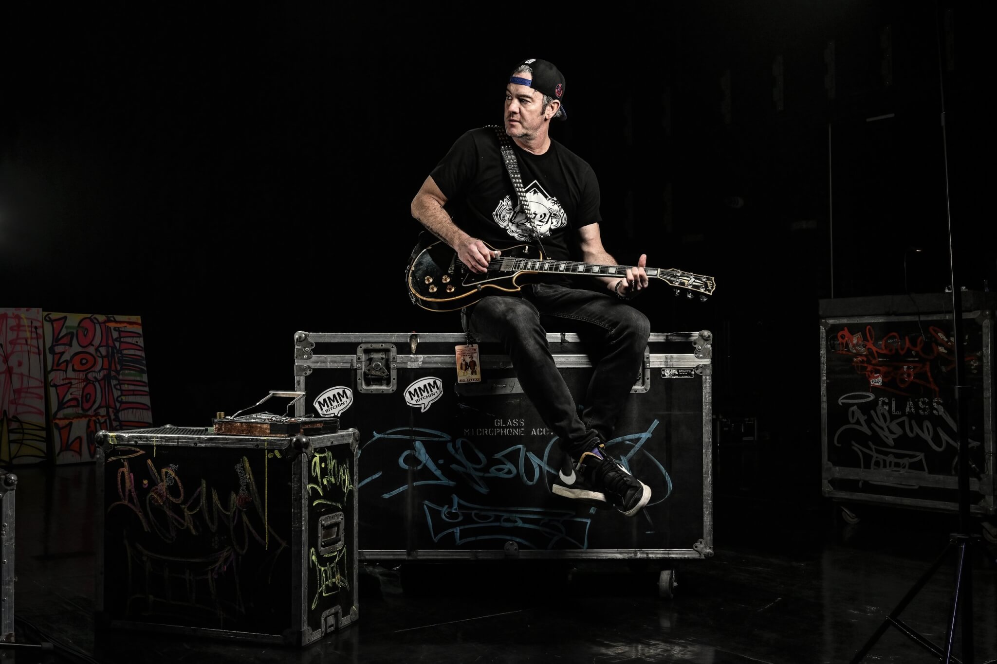 G. Love sitting on flight cases with an electric guitar