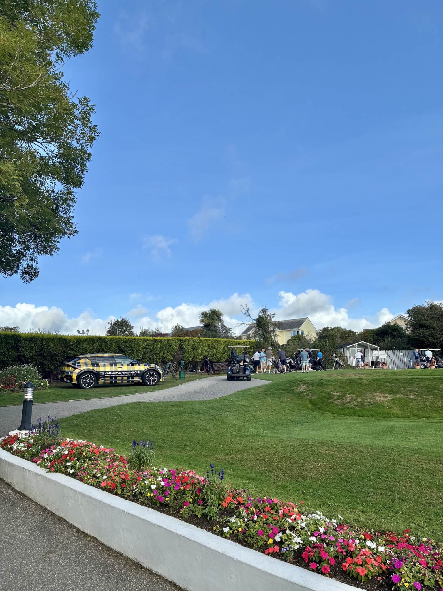 Hawkins tartan Kia EV6 parked near golfers at Carlyon Bay Golf Club