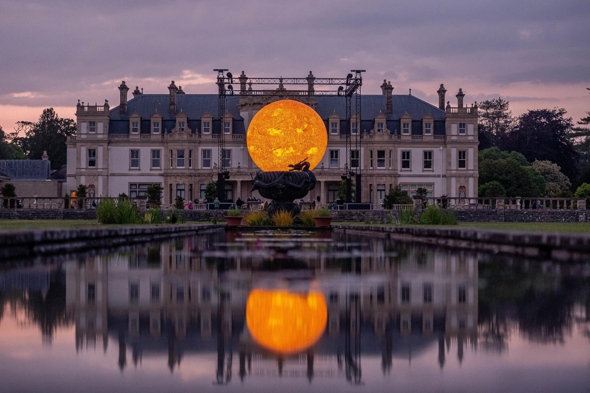 Helios Sun artwork reflected in the lake at Dyffryn Gardens at dusk