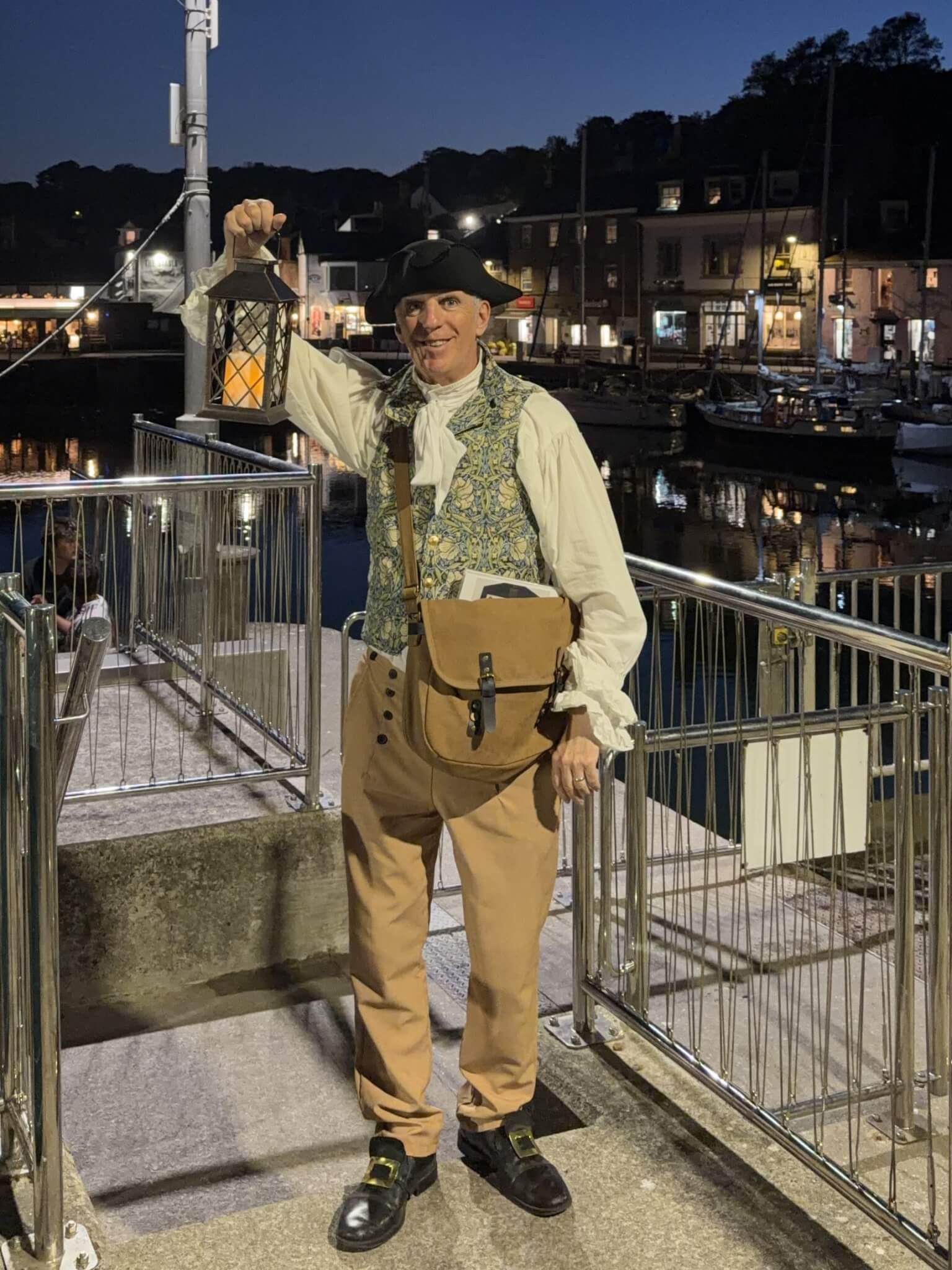 Ghost Walk Padstow guide in merchant costume with lantern and satchel on the harbourside