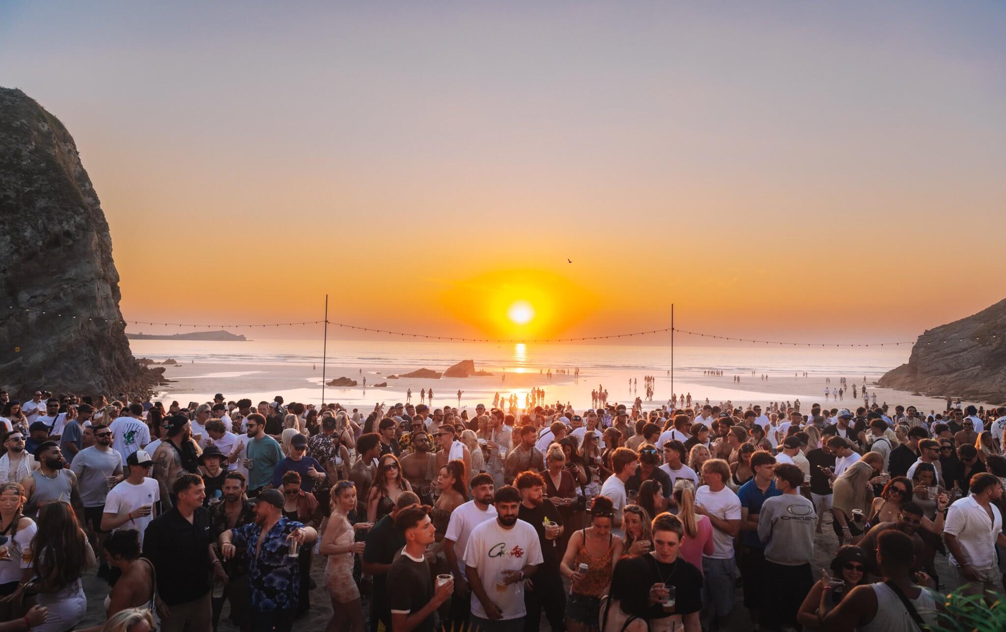Packed beach at Lusty Glaze as the sun sets