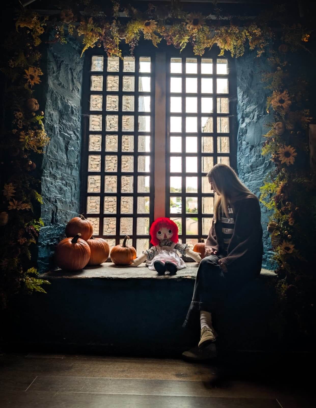 Visitor by a barred window with pumpkins at Bodmin Jail